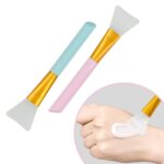 A pink and a blue silicone face mask applicator wand, side by side, showcasing their flexible bristles and ergonomic handles.