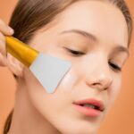 A pink and a blue silicone face mask applicator wand, side by side, showcasing their flexible bristles and ergonomic handles.